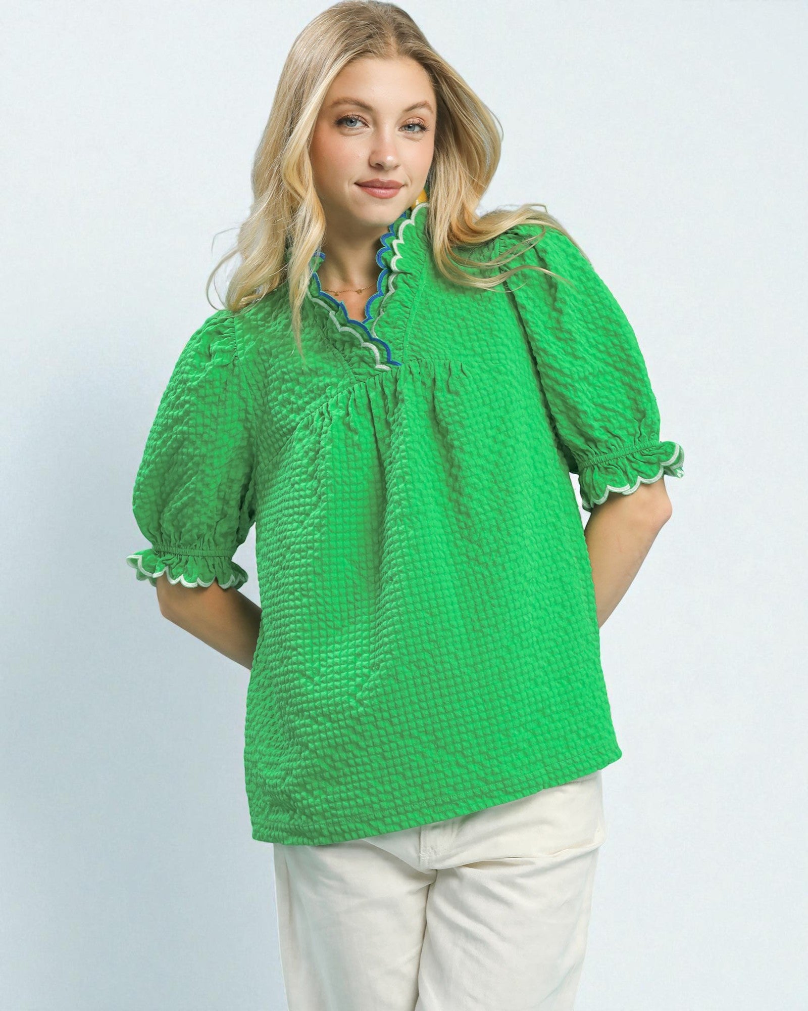 Woman wearing a green textured blouse with a plain background