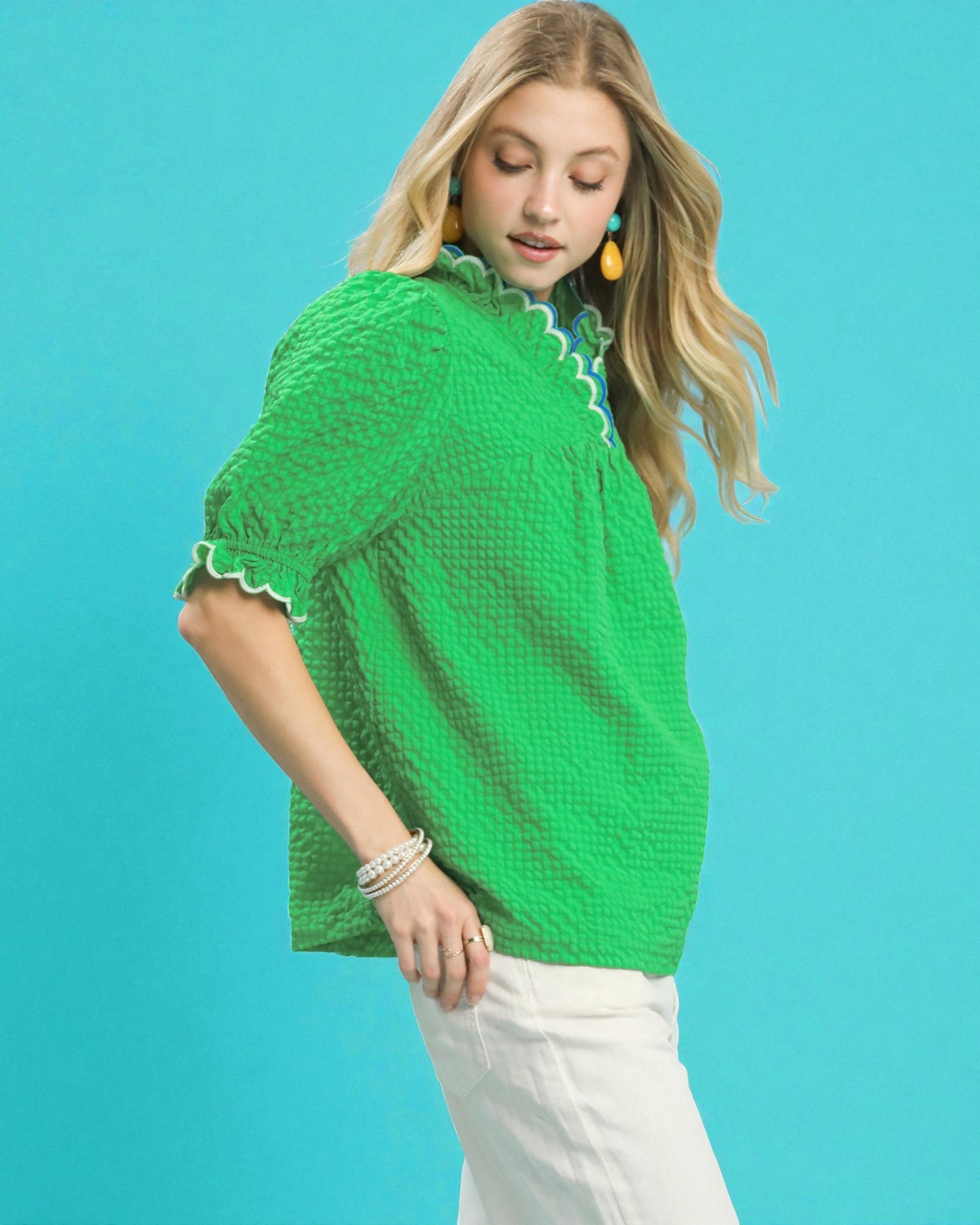 Woman wearing a green textured blouse against a blue background