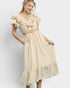 Woman wearing a beige dress with ruffled sleeves and a belt on a white background