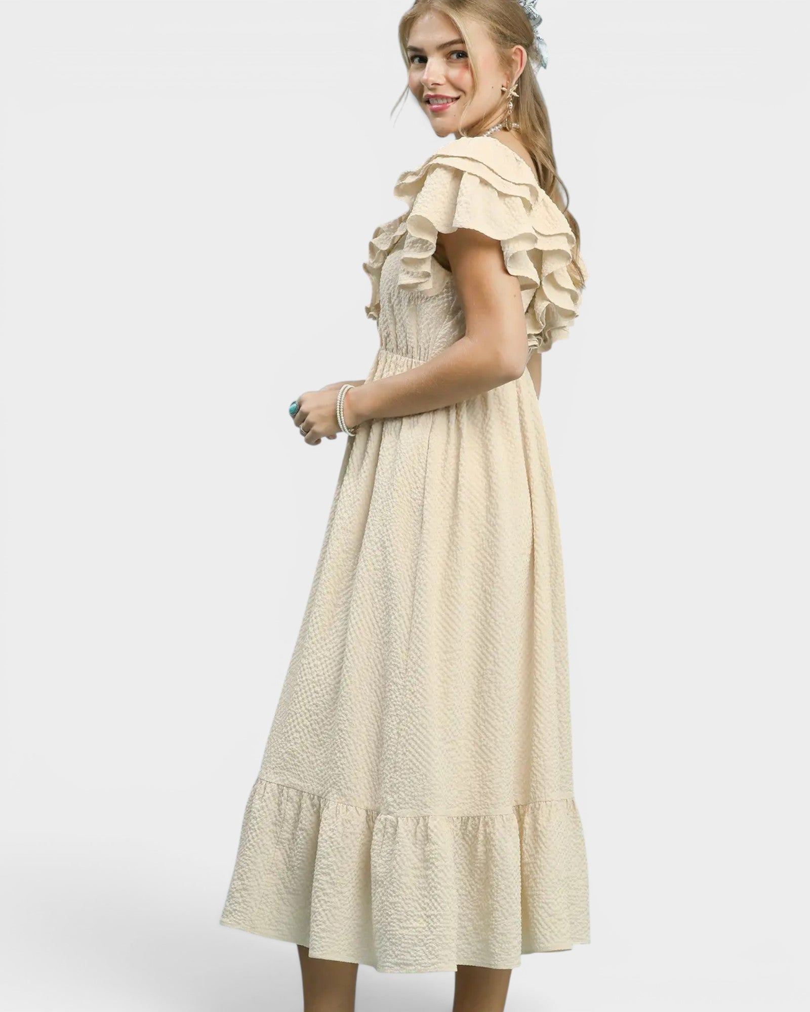 Woman wearing a beige dress with ruffled sleeves on a white background