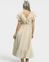 Woman wearing a beige dress with ruffled sleeves on a white background