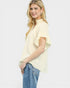 Woman wearing a light yellow blouse with ruffled sleeves and blue jeans on a white background