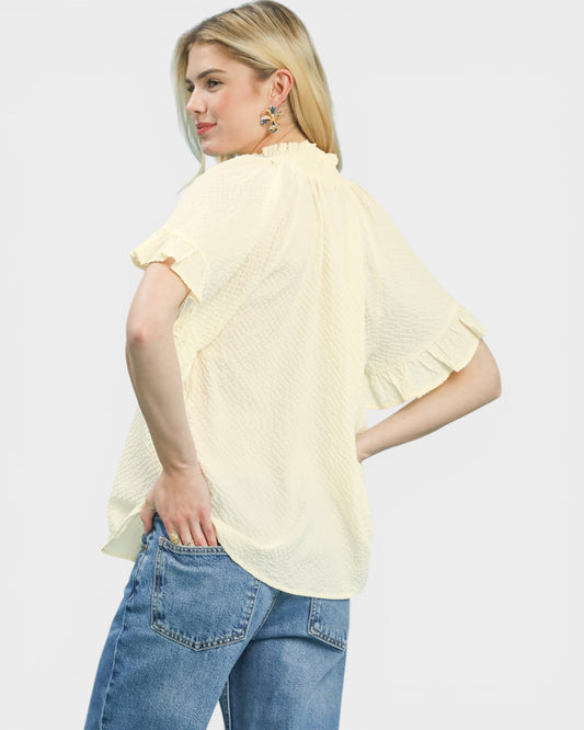 Woman wearing a light yellow blouse and blue jeans on a white background