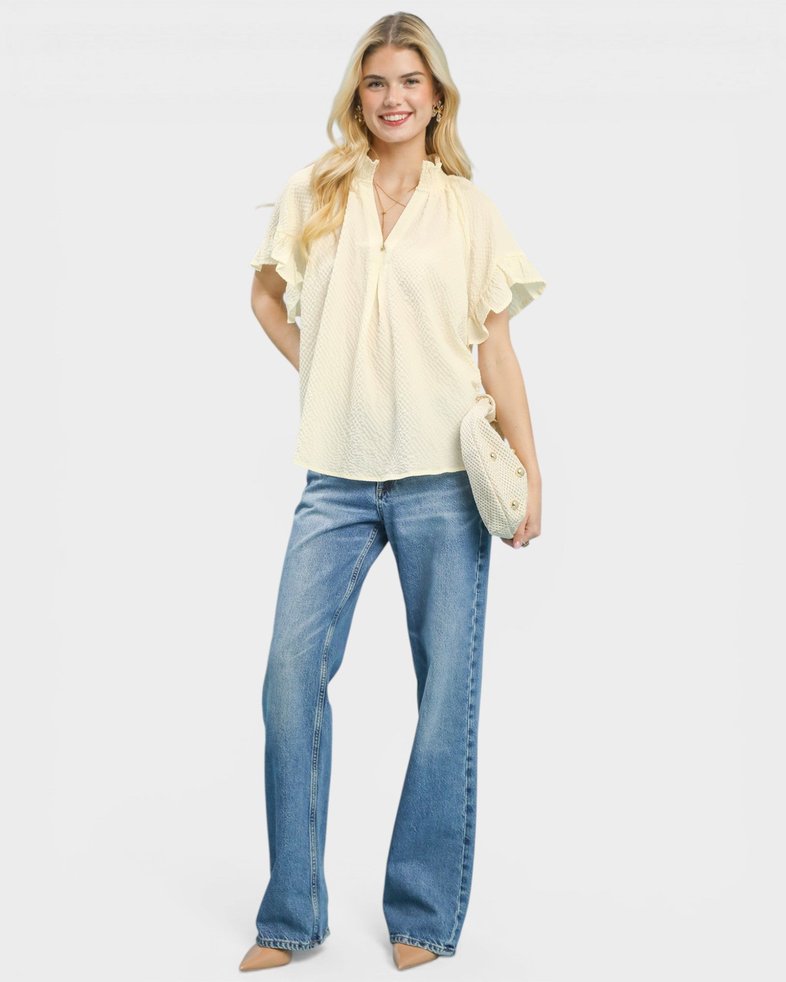 Woman wearing a light yellow blouse and blue jeans on a white background