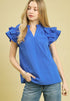 Woman wearing a blue blouse with ruffled sleeves against a beige background