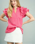 Woman wearing a pink blouse with ruffled sleeves and a white skirt on a gray background