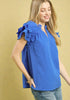 Woman wearing a blue top with ruffled sleeves against a beige background