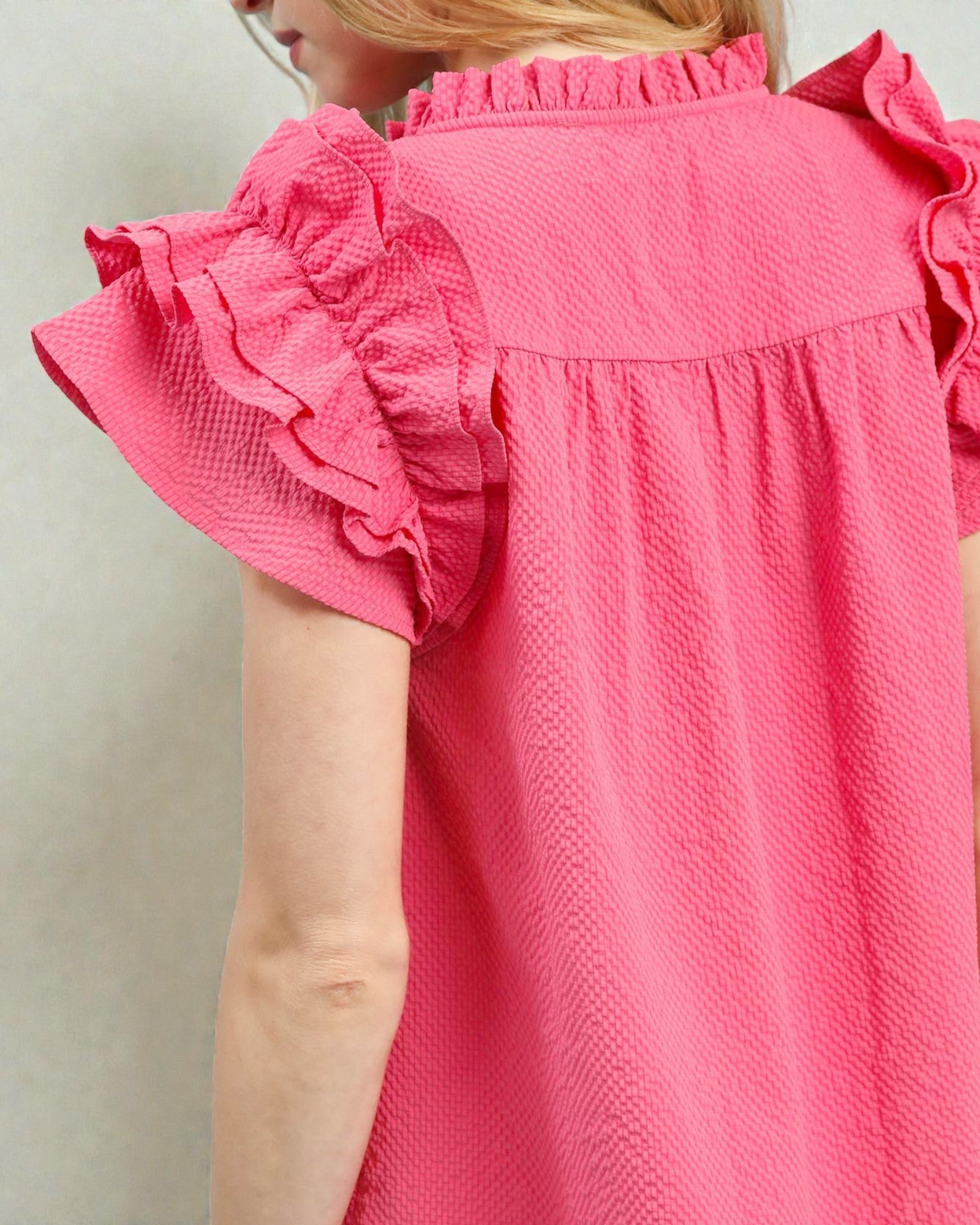 Close-up of a pink blouse with ruffled sleeves on a plain background