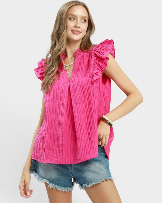Woman wearing a bright pink blouse with ruffled sleeves on a white background