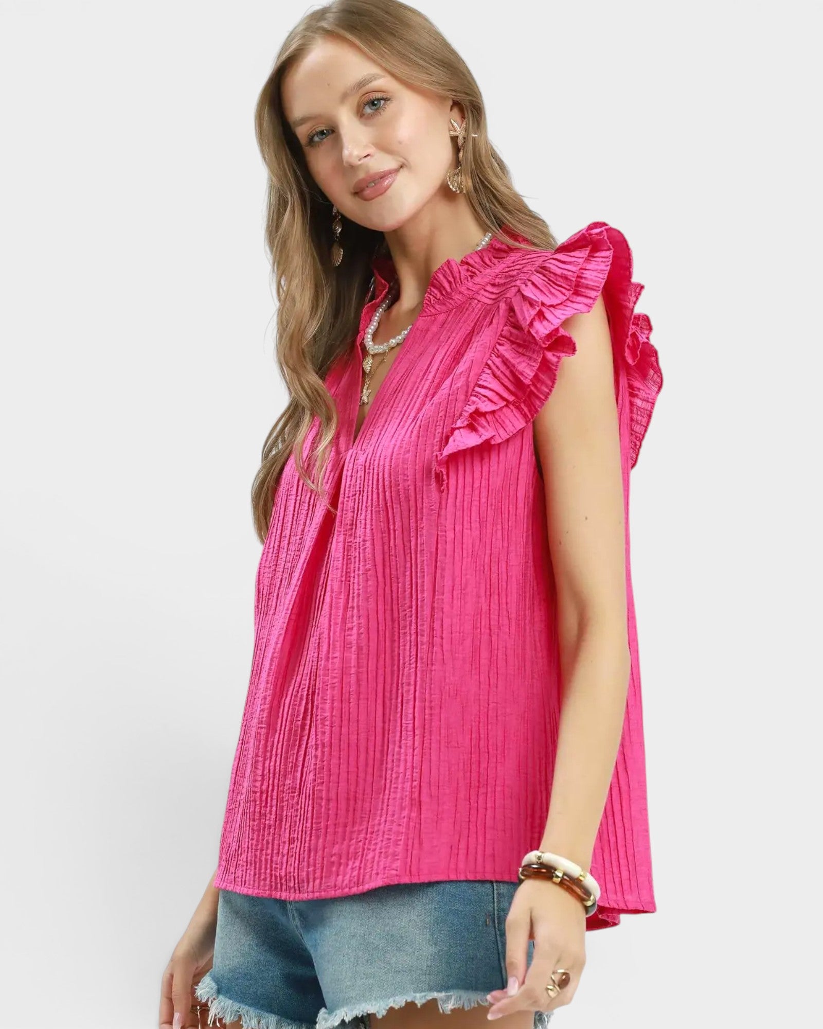 Woman wearing a bright pink ruffled blouse on a white background