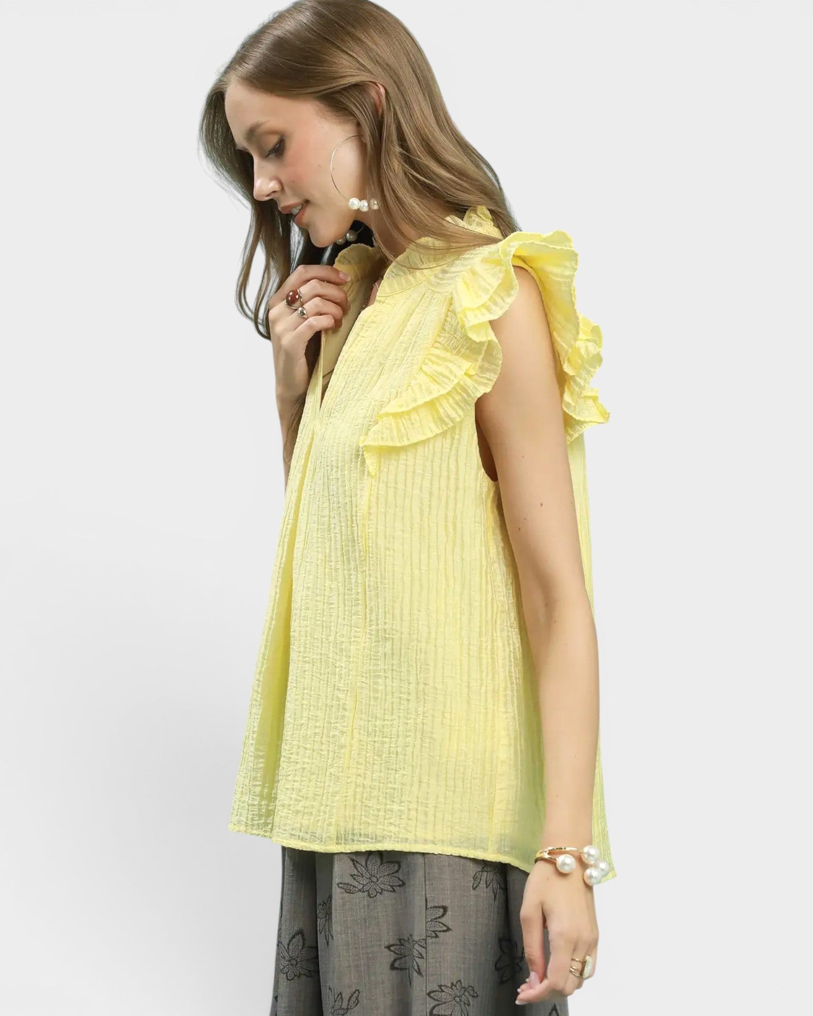 Woman wearing a yellow ruffled top on a white background