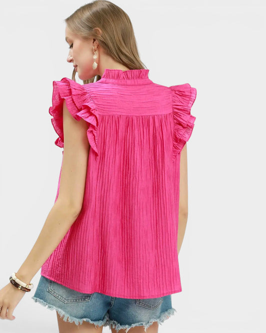 Woman wearing a bright pink sleeveless top with ruffled details on a white background