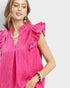 Woman wearing a bright pink dress with ruffled sleeves on a white background