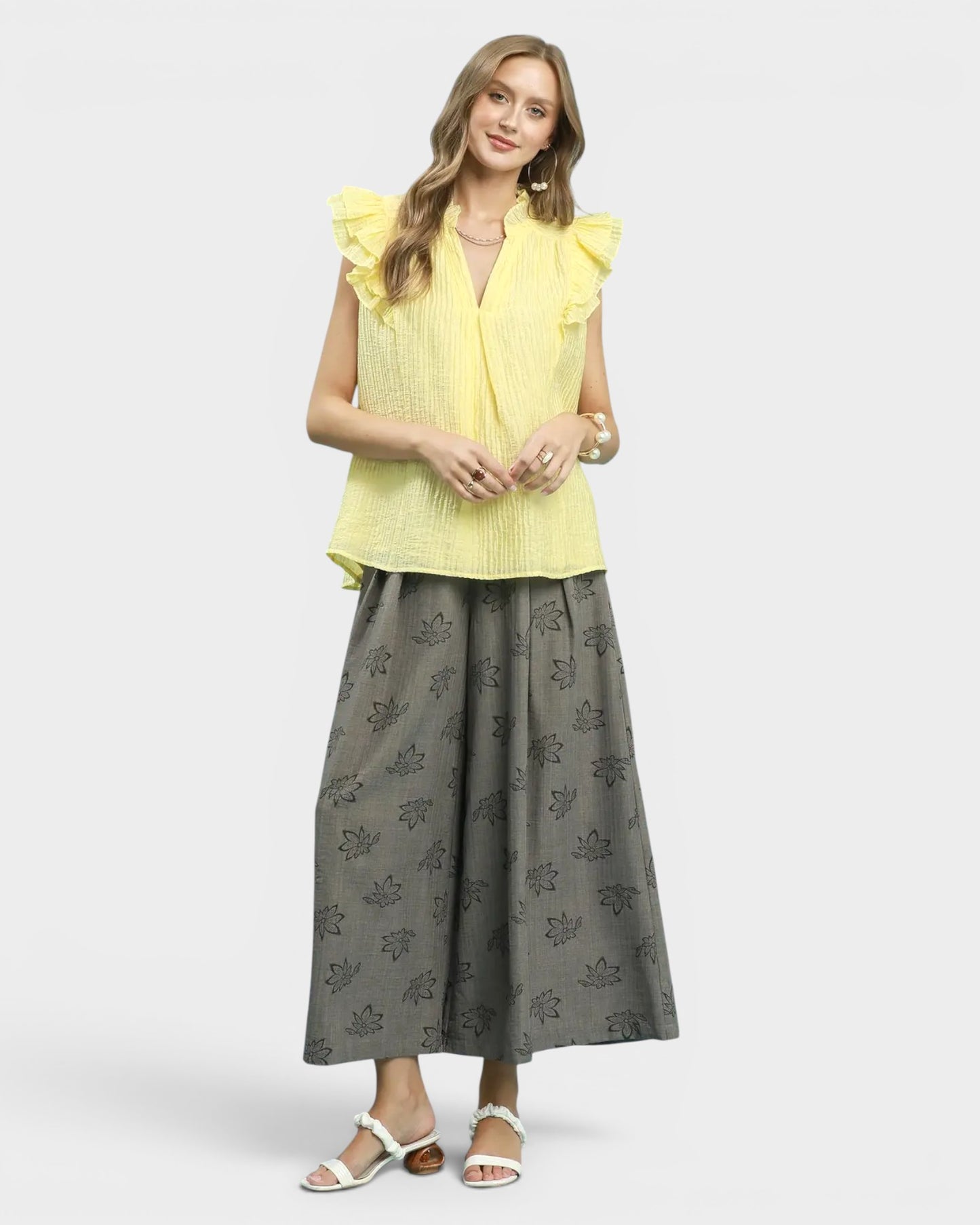 Woman wearing a yellow top and gray skirt on a white background