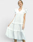 Woman wearing a white dress with ruffled sleeves and layers on a light gray background