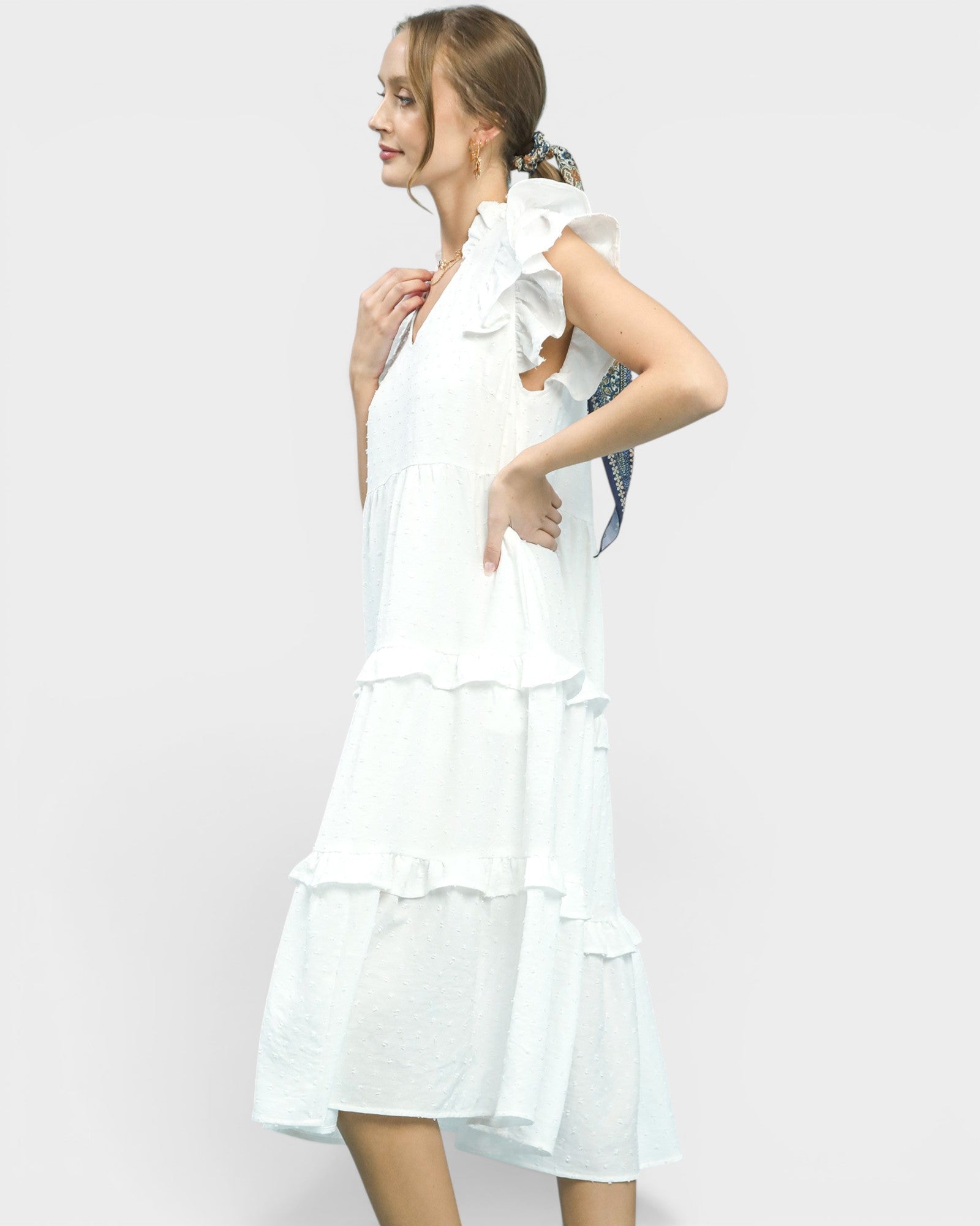 Woman wearing a white dress with ruffled layers on a plain background