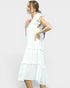 Woman wearing a white dress with ruffled layers on a plain background