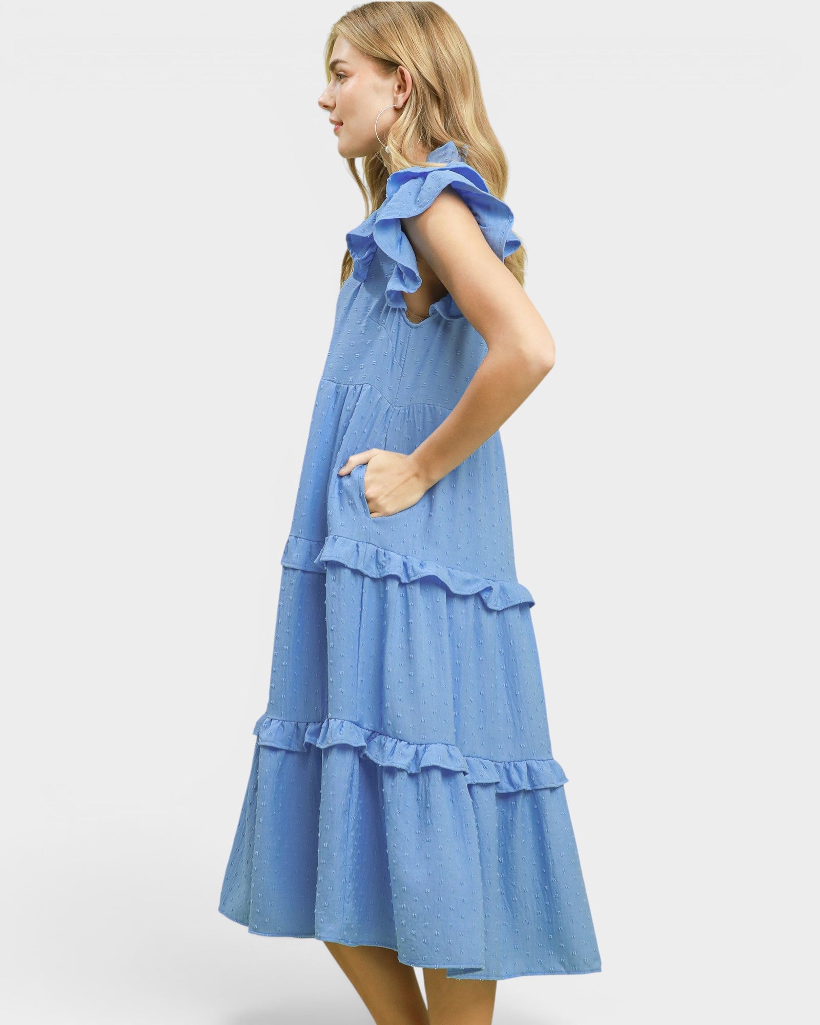 Woman wearing a blue dress with ruffled details on a white background