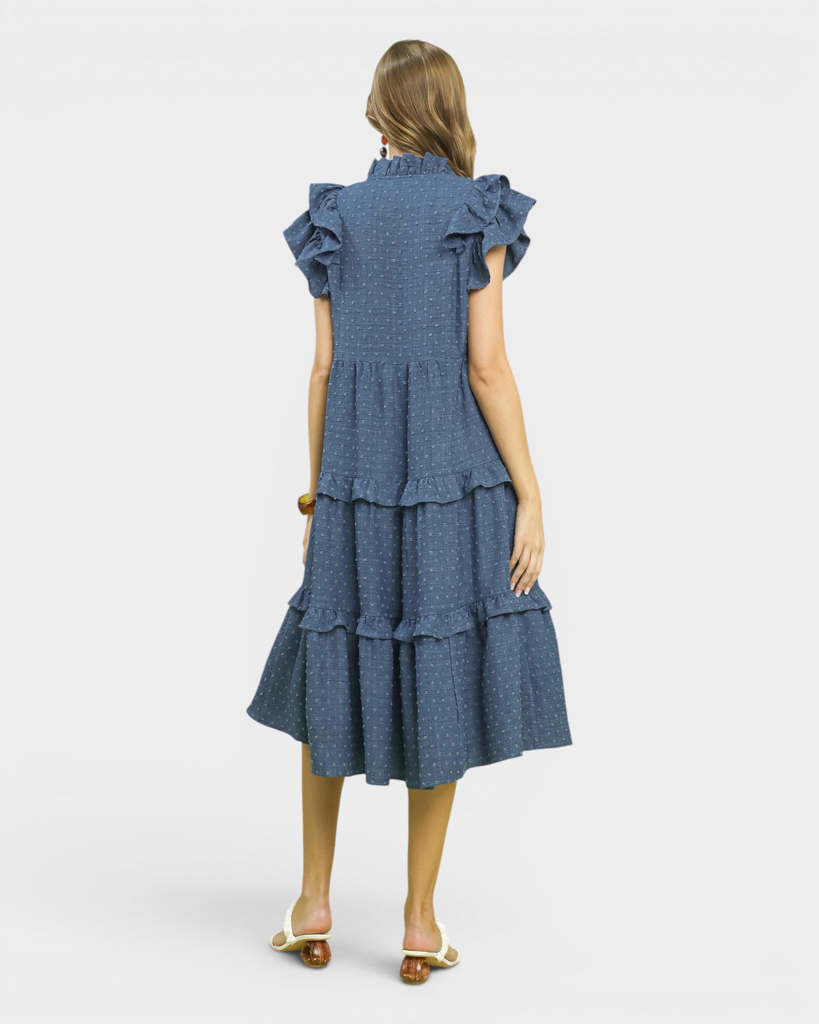 Woman wearing a blue tiered dress on a white background
