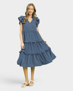 Woman wearing a blue tiered dress on a white background