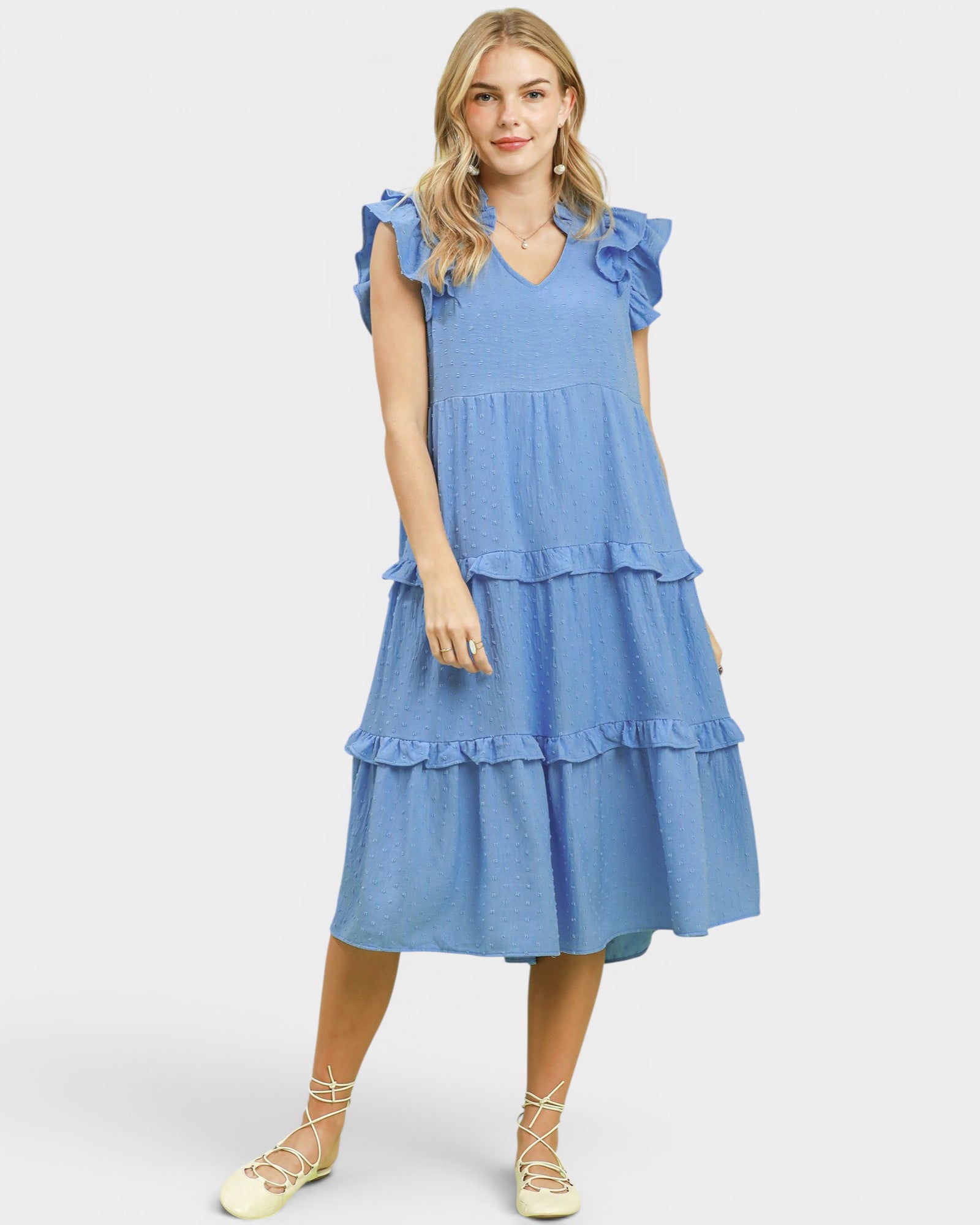 Woman wearing a blue tiered dress on a white background
