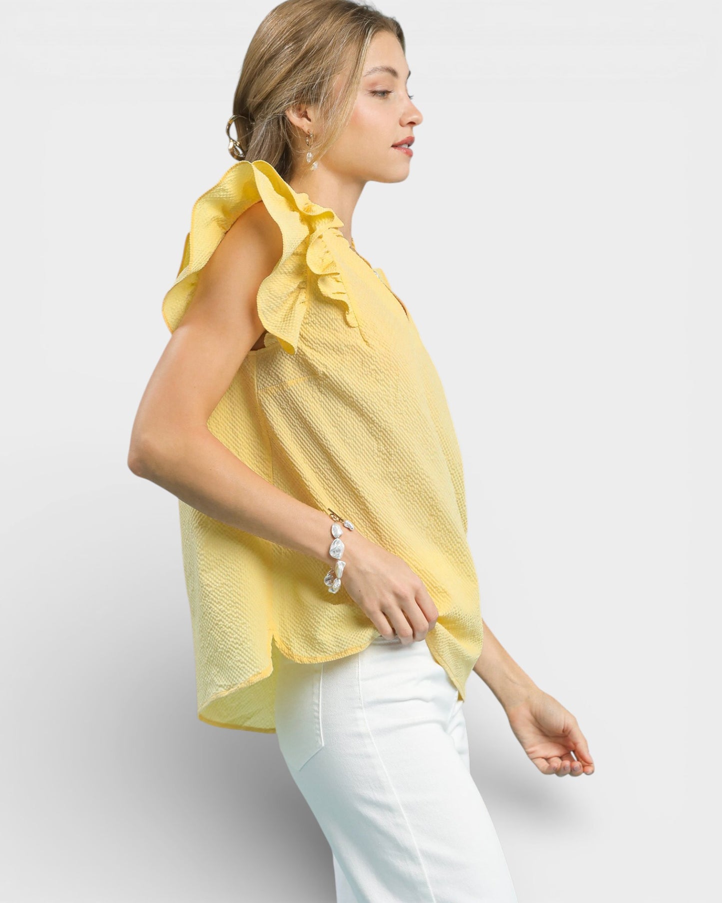 Woman wearing a yellow blouse with ruffled sleeves on a white background