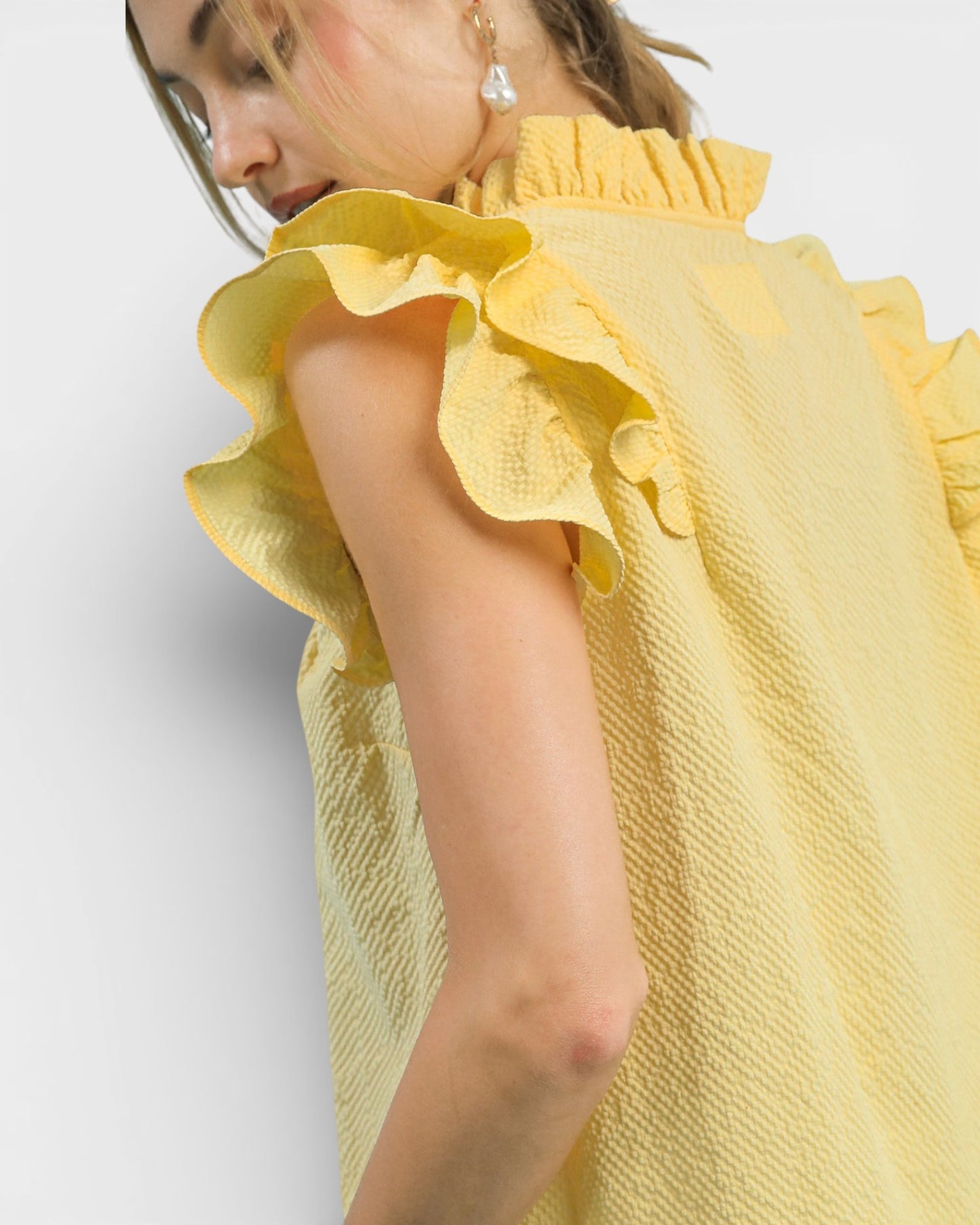 Yellow dress with ruffled sleeves worn by a person on a light gray background