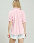 Person wearing a pink blouse and white shorts on a plain background