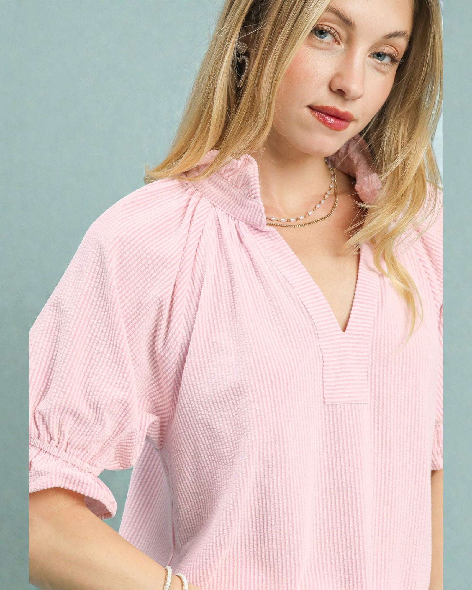 Woman wearing a pink blouse against a light blue background