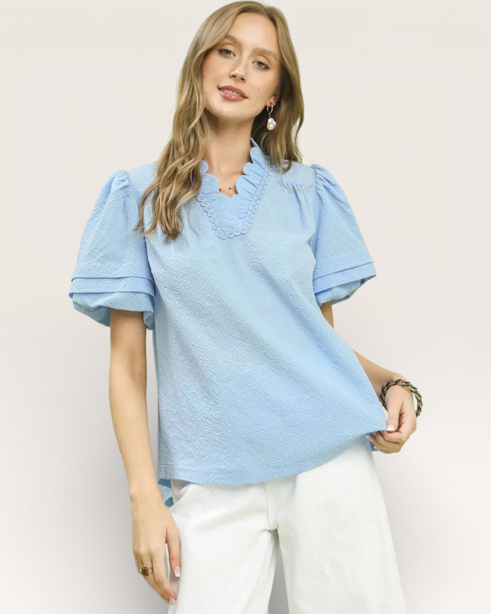 Woman wearing a light blue blouse with puff sleeves against a plain background