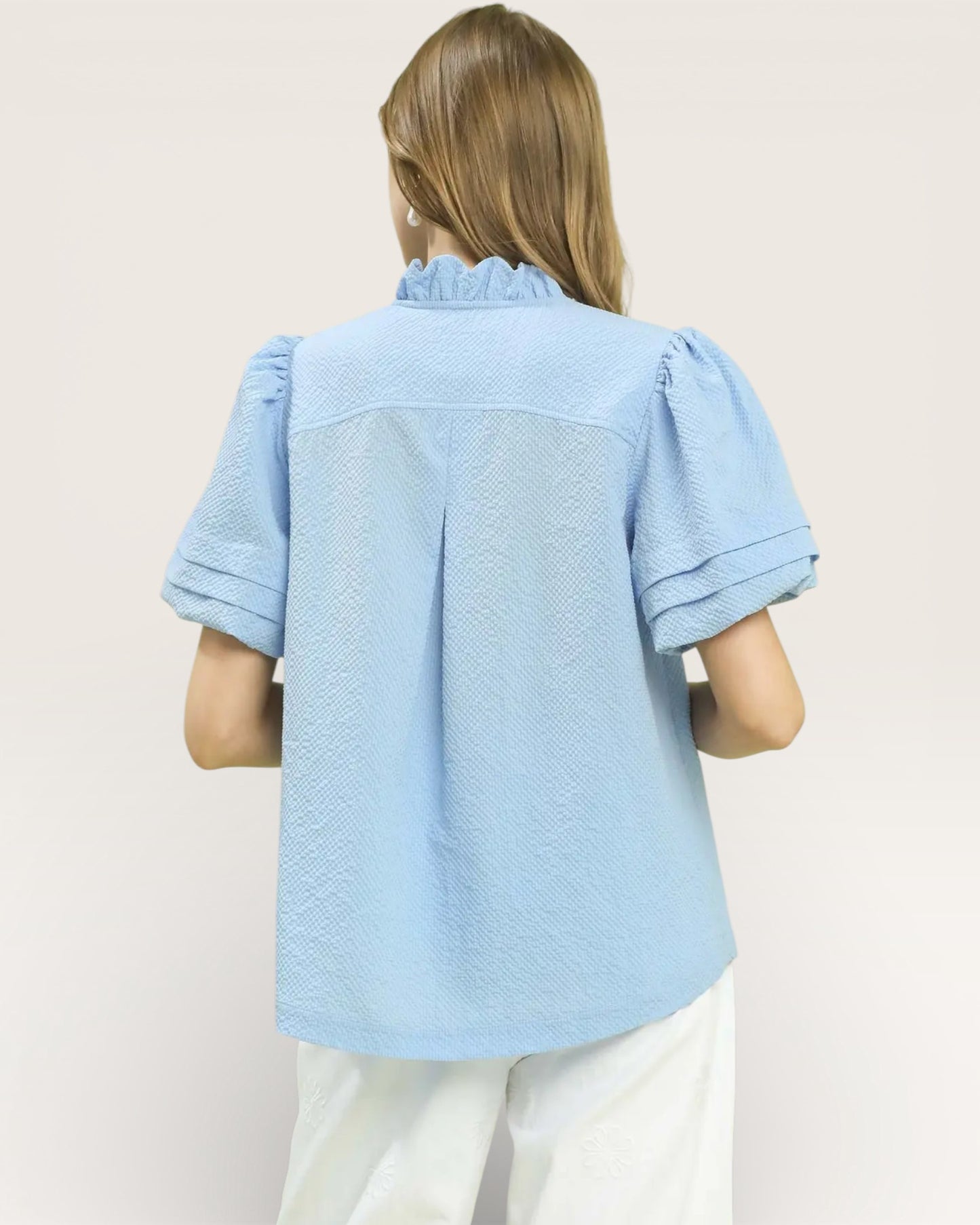 Person wearing a light blue textured shirt on a plain background