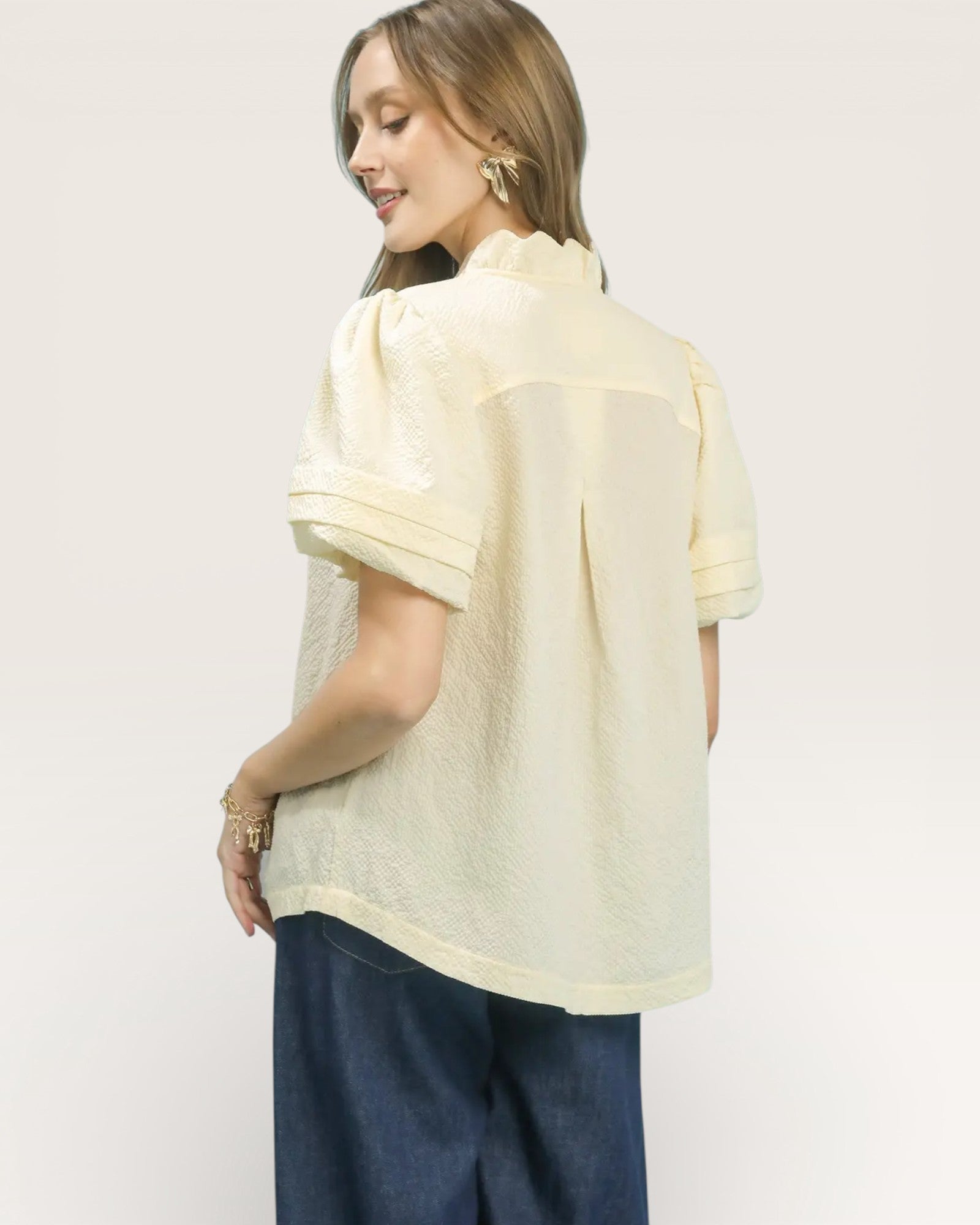 Woman wearing a light yellow blouse with a plain background