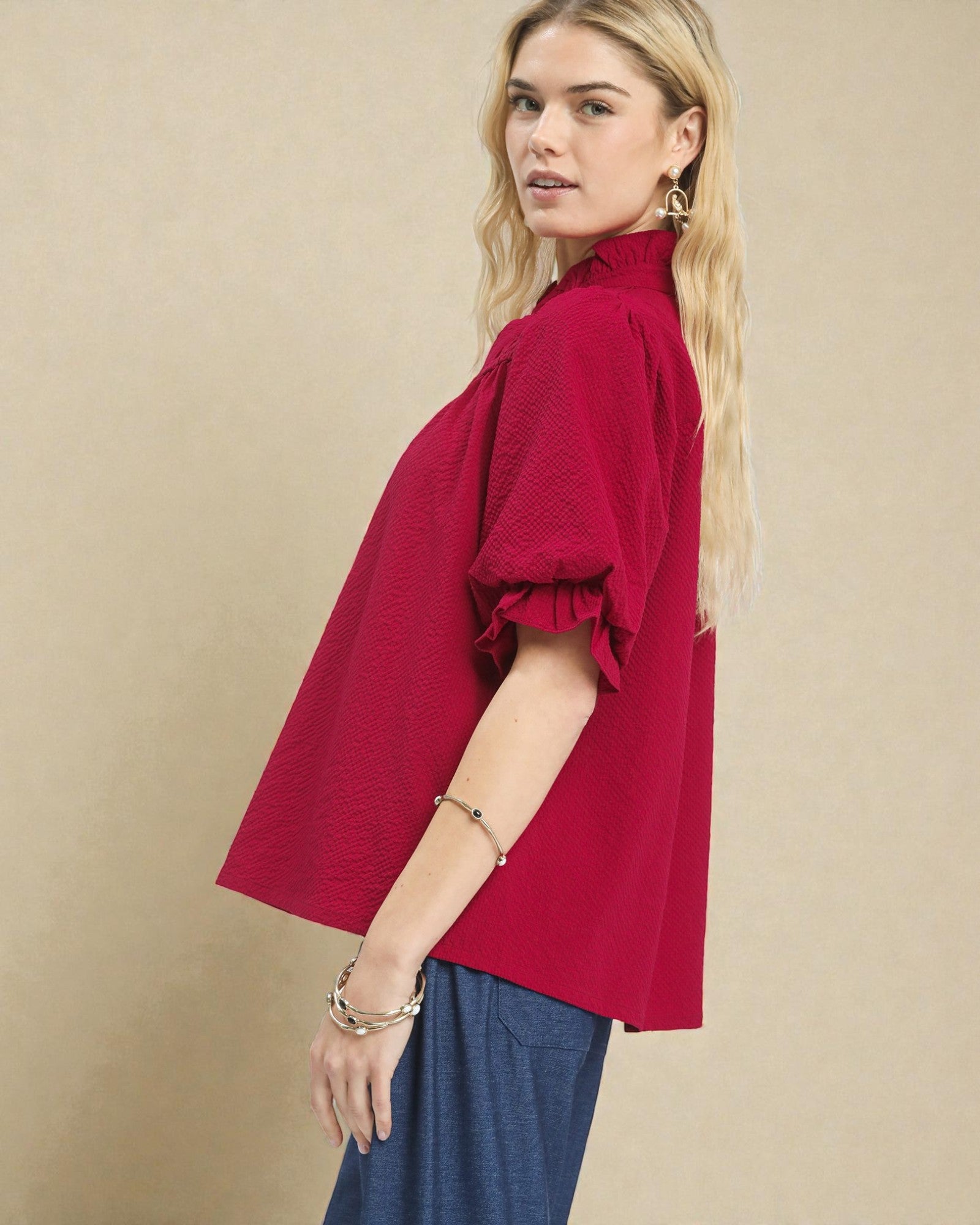 Woman wearing a red blouse with ruffled sleeves on a beige background