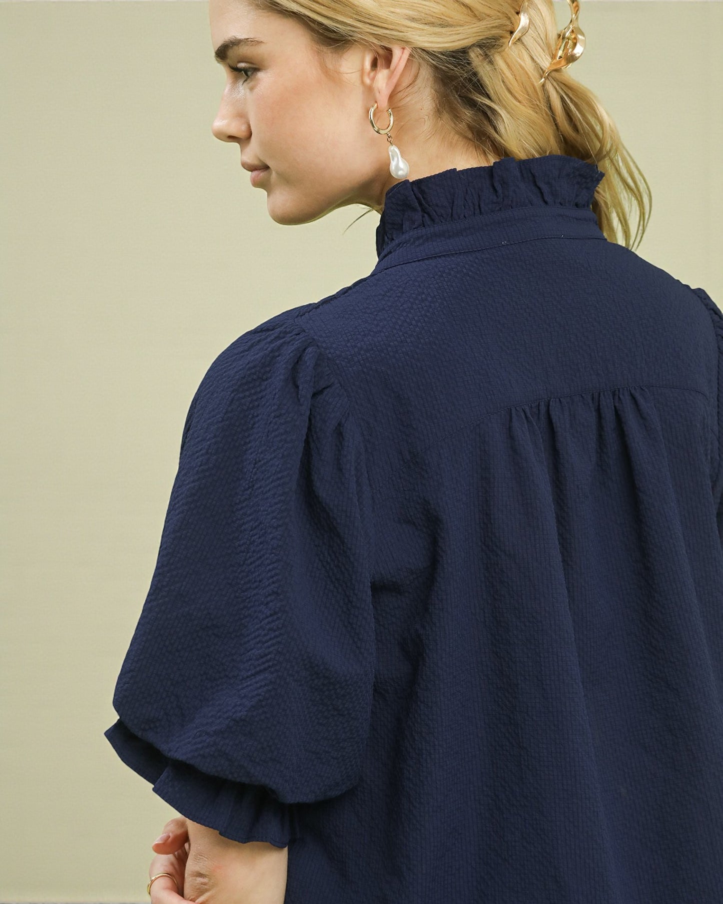 Person wearing a navy blue blouse with a plain background