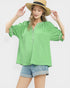 Woman wearing a green blouse and denim shorts with a straw hat on a white background