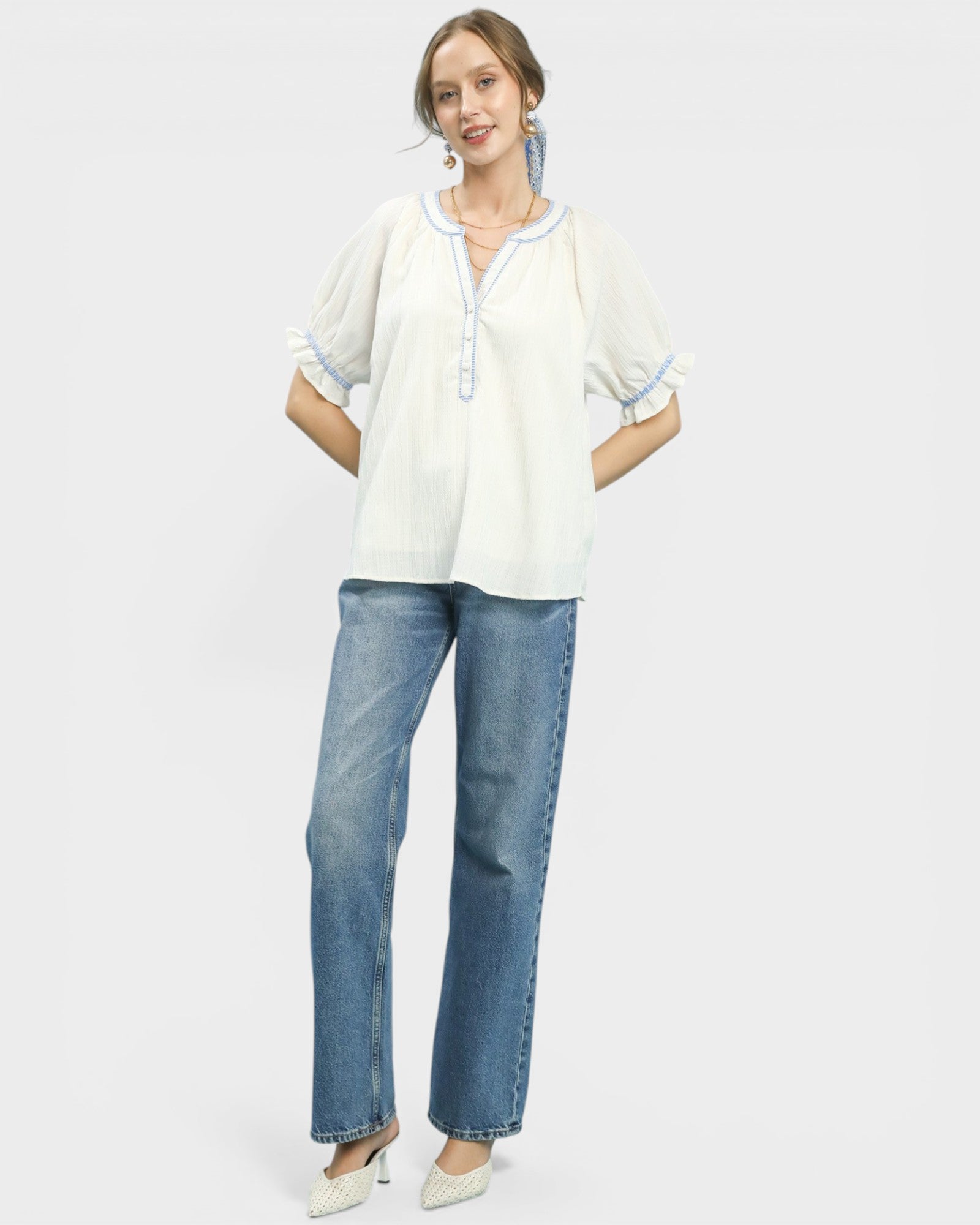 Woman wearing a white blouse and blue jeans on a plain background