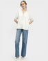 Woman wearing a white blouse and blue jeans on a plain background