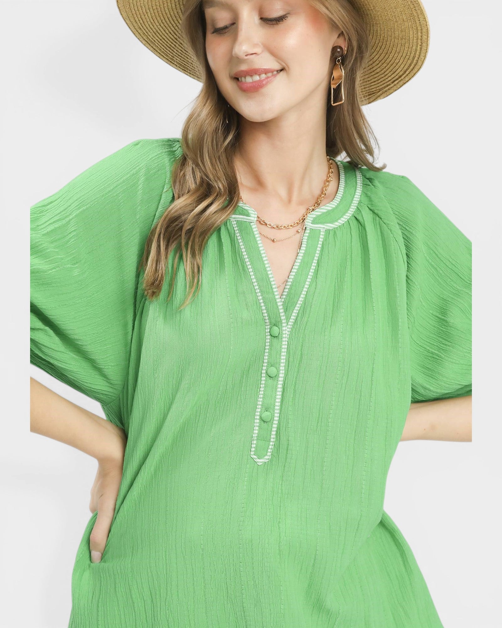 Woman wearing a green dress with a pearl necklace against a white background