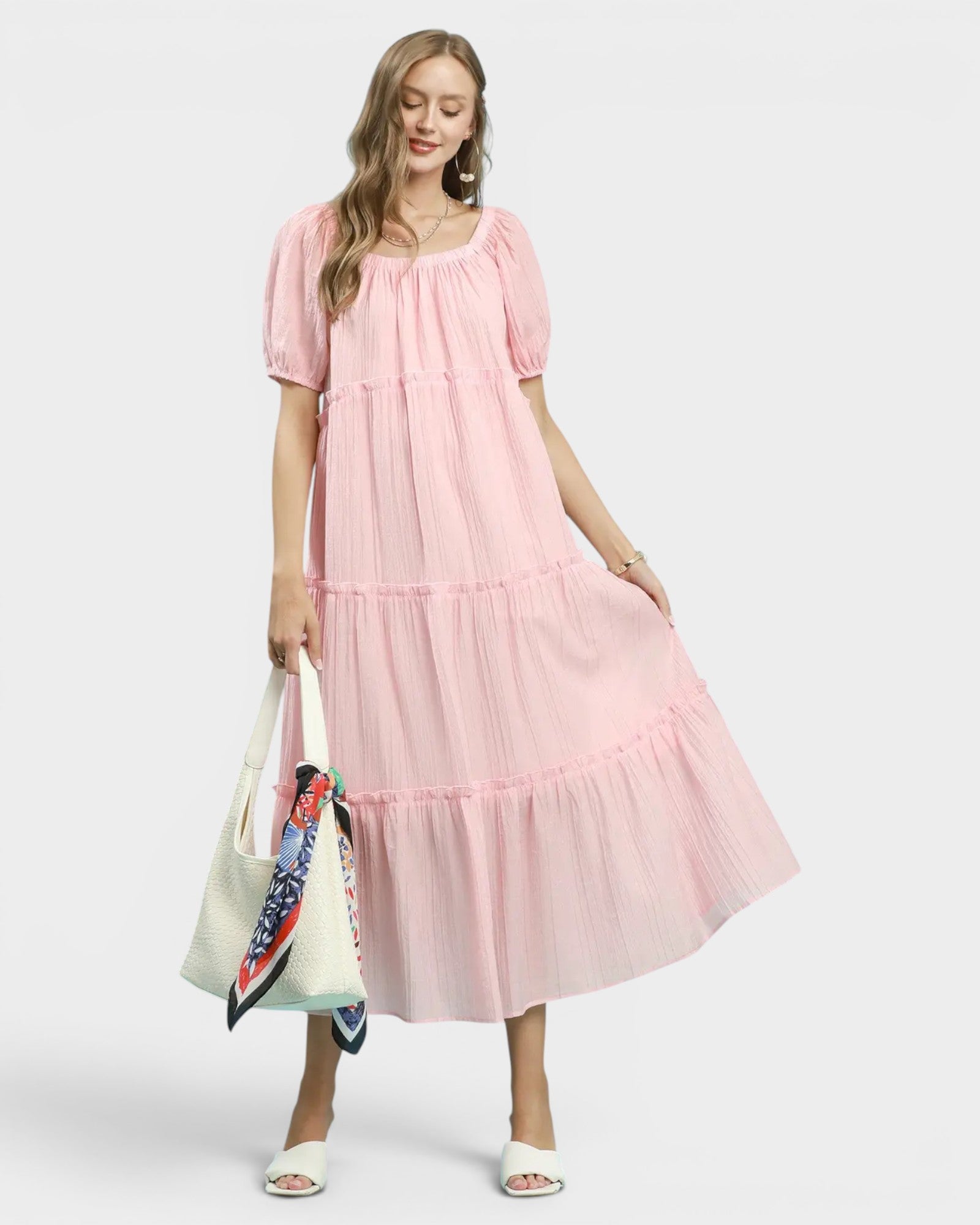 Woman wearing a pink dress holding a colorful bag on a white background
