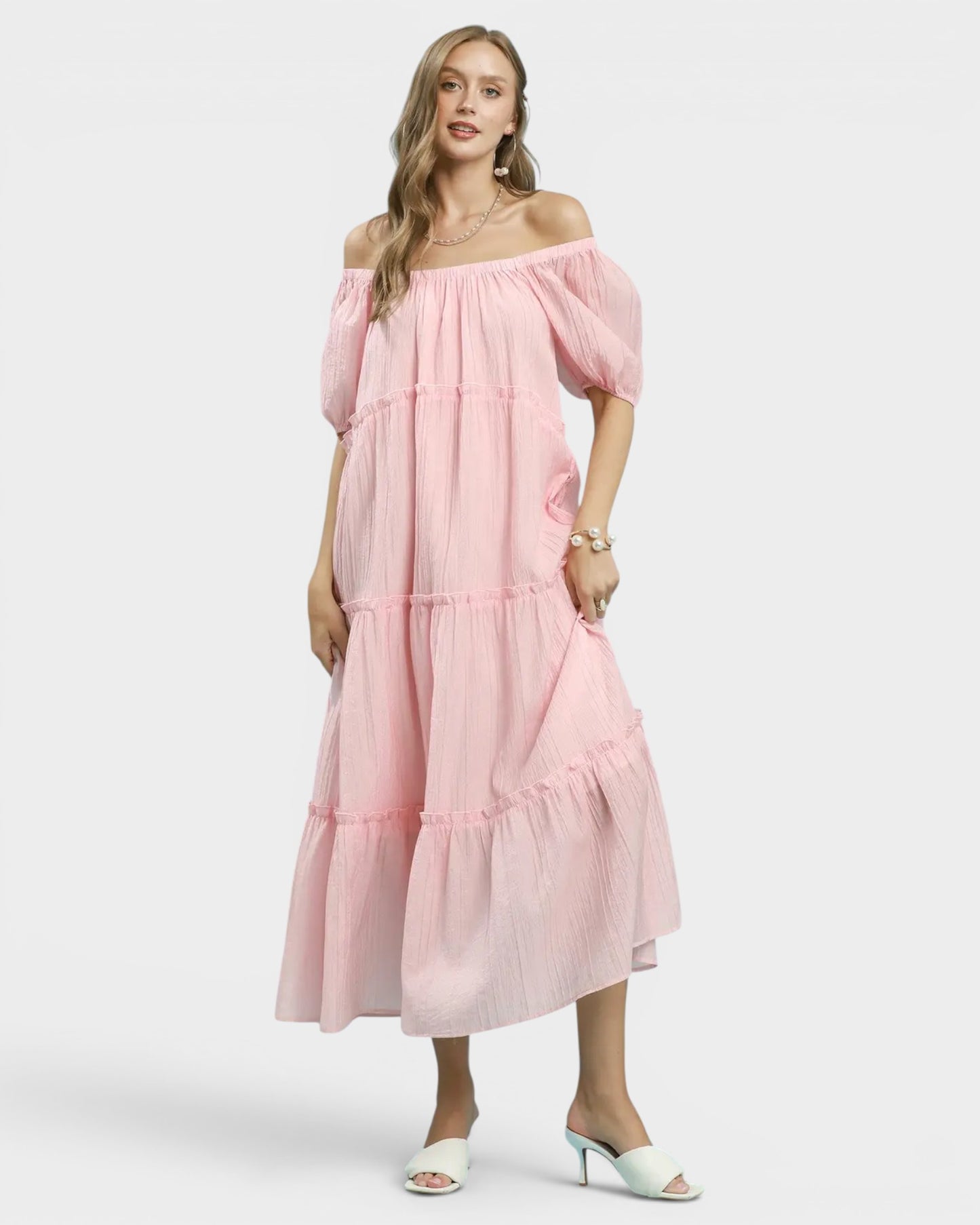 Woman wearing a pink off-shoulder dress on a white background