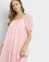 Woman wearing a pink dress with puffed sleeves on a light gray background