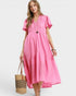 Woman wearing a pink dress holding a straw bag on a white background