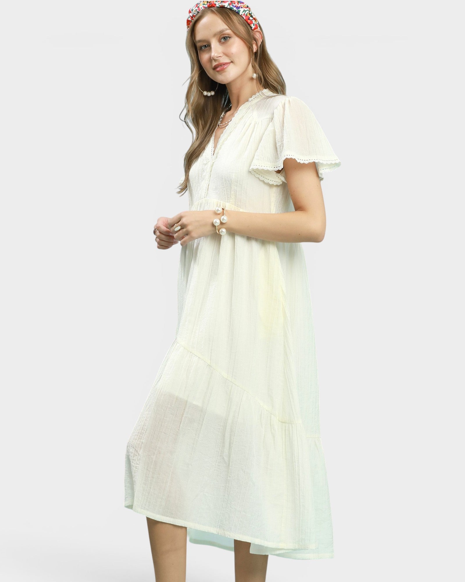 Woman wearing a light-colored dress with ruffled sleeves on a white background