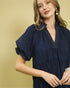 Woman wearing a navy blue dress with a gold background