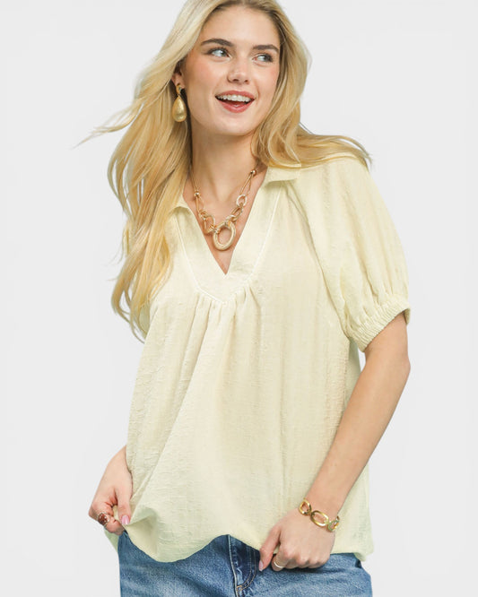 Woman wearing a light yellow blouse with a plain background