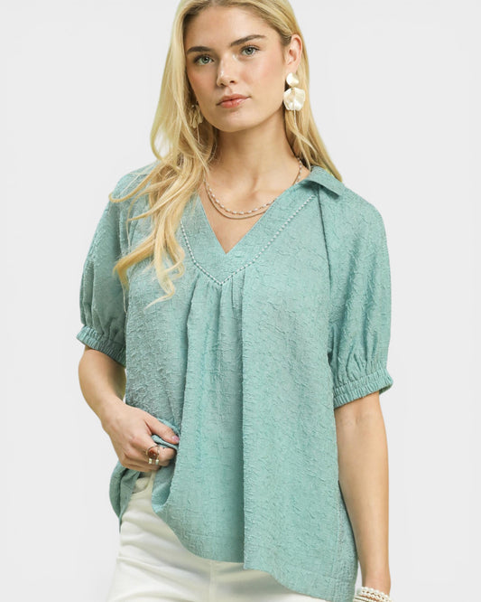 Woman wearing a light green blouse with puff sleeves on a white background