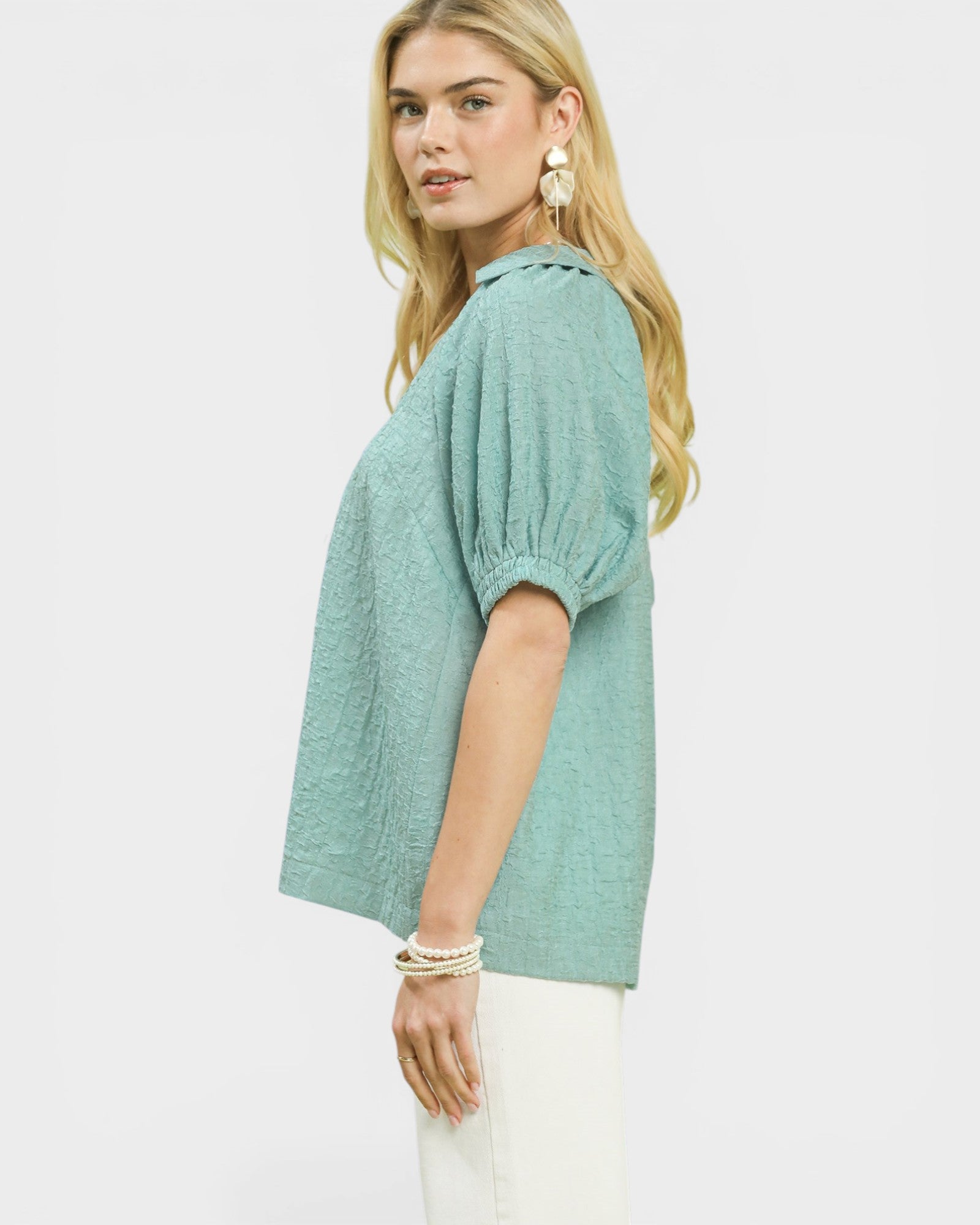 Woman wearing a green blouse with short sleeves on a white background