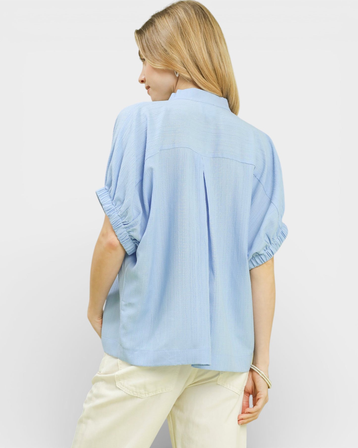 Woman wearing a light blue shirt and beige pants on a white background