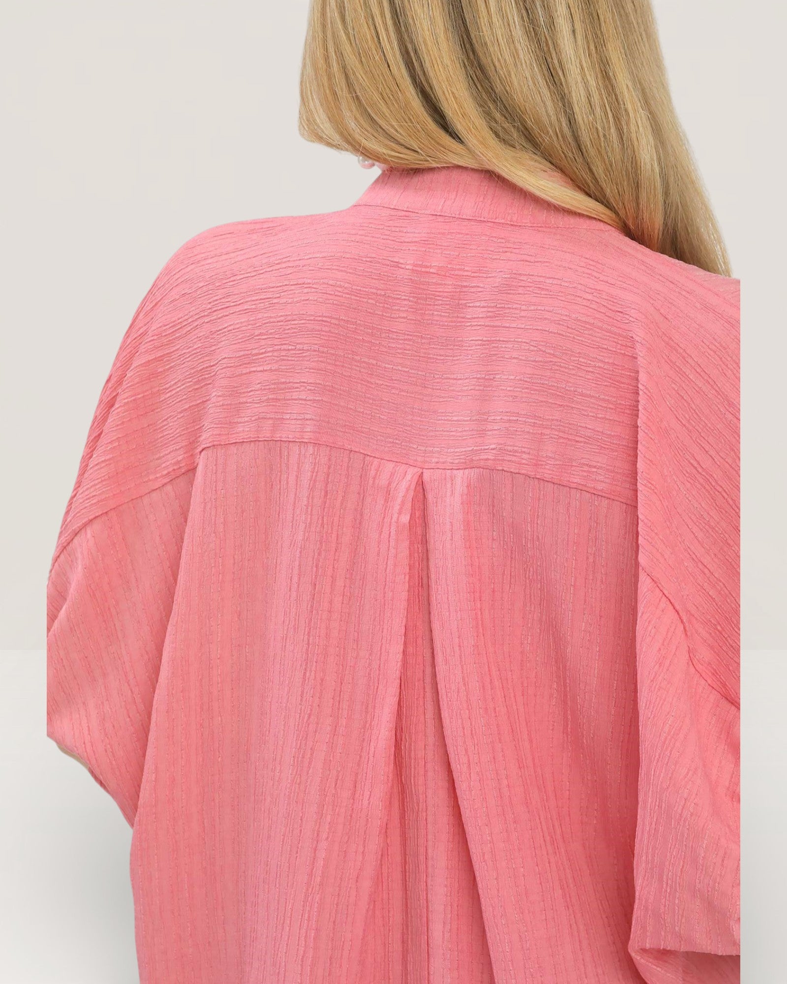 Pink blouse worn by a person on a plain background