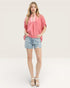 Woman wearing a pink top and denim shorts on a white background